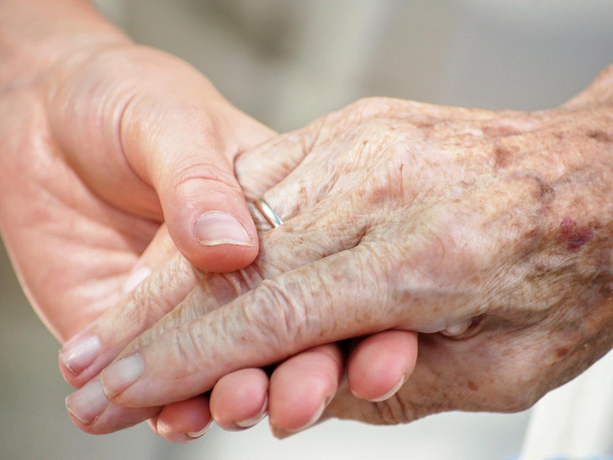 Nahaufnahme zweier Hände, eine ältere und eine jüngere, die sich liebevoll halten.
